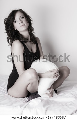 Sexy lazy girl in black body hugging a pillow on the bed. Young attractive woman relaxing lazing in her bedroom at the morning.