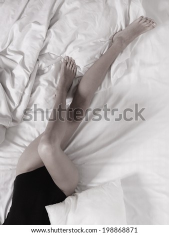 Closeup of sexy female legs on the bed. Woman lazy girl relaxing lazing in bedroom.