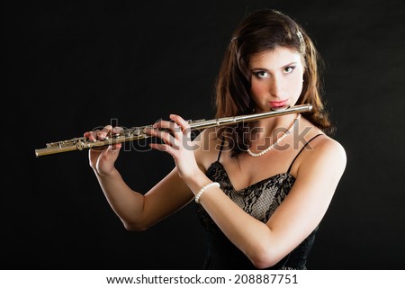 Art and artist. Young woman elegant girl flutist flautist musician performer playing flute musical instrument on black. Classical music.