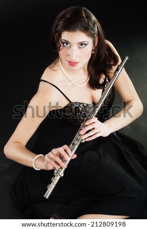 Art and artist. Portrait of woman girl flutist flautist performer with flute musical instrument on black. Classical music.
