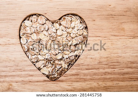 Dieting health care concept. Oat cereal oatmeal heart shaped on wooden surface. Healthy food for lowering cholesterol.