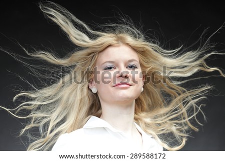 Blonde woman with her hair blowing in the wind on black