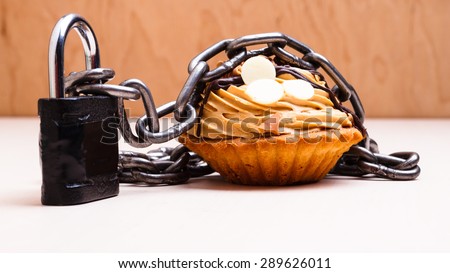 Diet sugar sweet food addiction concept. Cake cupcake wrapped in metal chain and padlock