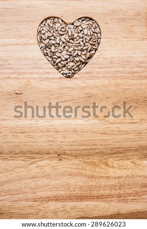 Whole food. Heart shaped sunflower seeds on wood surface background