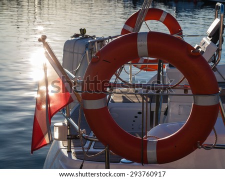 Closeup rescue red lifebuoy life preserver saver ring on sailboat and polish ensign flag