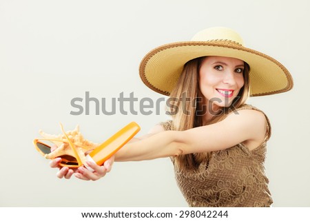 Holidays summer fashion and skin care concept. Woman in straw hat holds sunglasses shell and sunscreen lotion, gray background copy space