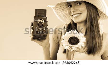 summer woman wearing hat with sunflower and old vintage camera in hand sepia filter