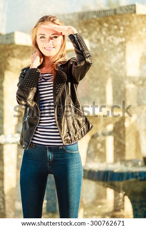 Fashion young blonde woman casual style posing against city fountain