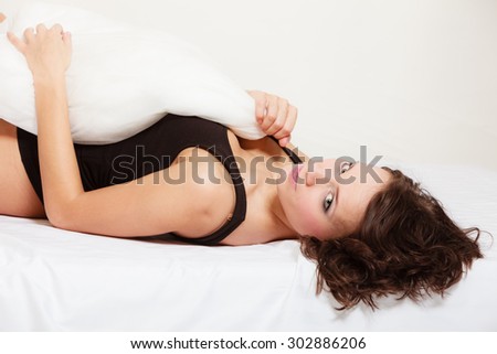 Sexy lazy girl in black body lying with pillow on the bed. Young attractive woman relaxing lazing in bedroom at morning.