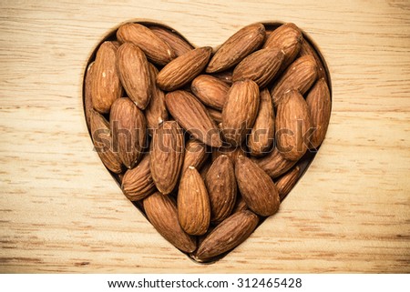 Whole food, good for health. Heart shaped almonds on wooden surface board background