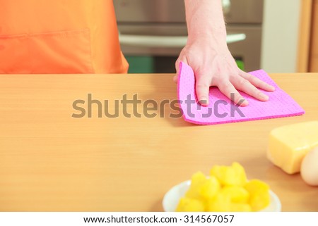 People, housework and housekeeping concept - closeup male hand cleaning table with rag at home kitchen