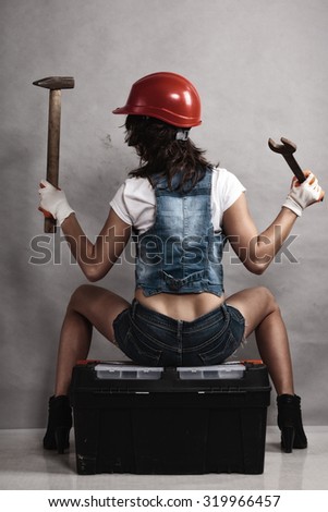 Sex equality and feminism. Back of sexy girl sitting on toolbox holding wrench spanner and hammer. Woman working as mechanic.