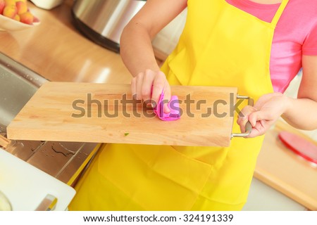 People, housework and housekeeping concept. Woman doing the tidying up in kitchen cleaning wooden cutting board with rag sponge