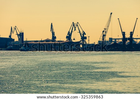 Business and commerce. Heavy load dockside cranes in port, cargo container yard. Industrial scene