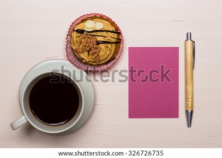 coffee cup sweet cake cupcake and pink paper blank with pen on wooden surface, top view copy space for text