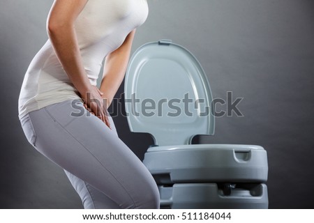 Sick woman with hands holding pressing her crotch lower abdomen in front of toilet bowl. Medical problems, incontinence, health care concept