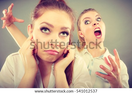 Conflict, bad relationships, friendship difficulties. Two young women having argument. Angry fury girl screaming at her friend or younger sister, female closing his ears, not listening