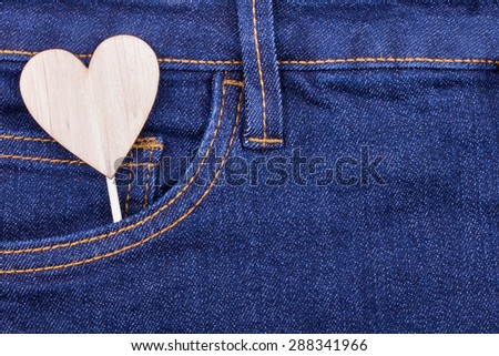 Denim texture background and pocket with wooden heart shape, declaration of love concept.