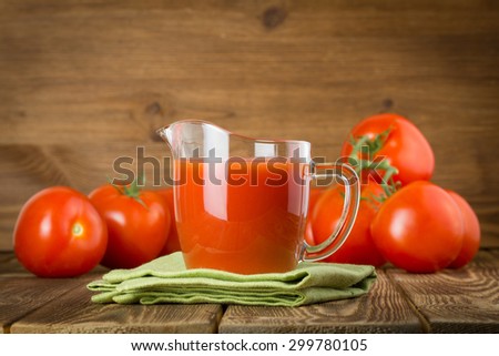 Glass jug with fresh tomato sauce on rustic wooden surface