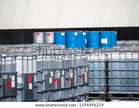 Blue oil drums and white IBC container on a chemical storage site