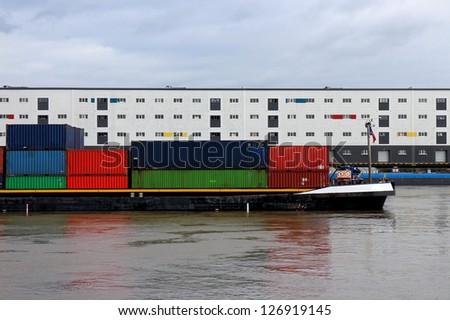Container ship on a river with storage buildings in the background