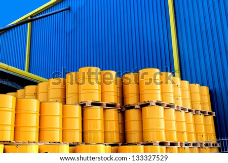 Yellow oil drums in front of a factory with blue cladding