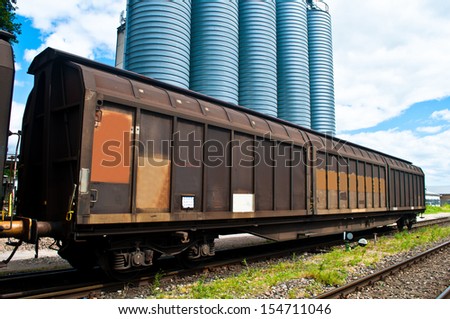 Train wagon on a railroad with blue silos in the background