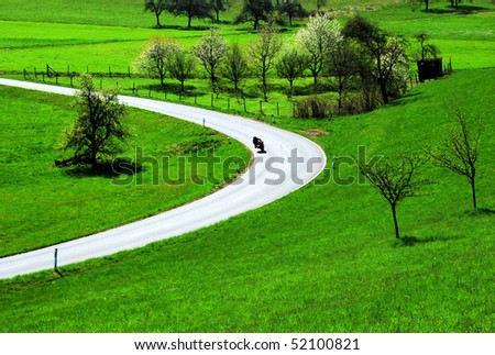 Motorbike rider in a street curve in a rural landscape