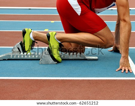 Man in a start block on an athletic track
