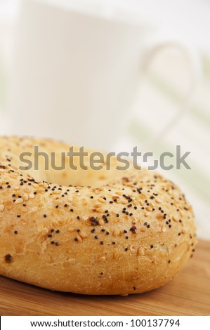 Fresh bagel with seeds and coffee mug in the background