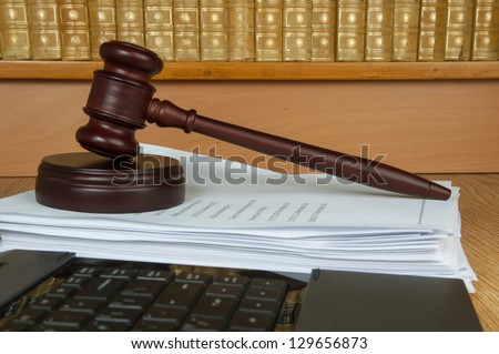 Judge gavel with computer and old legal books in the background