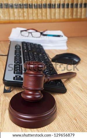 Justice gavel with computer and old legal books in the background