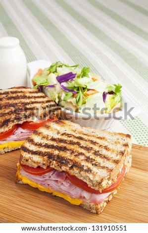 Italian grilled sandwich with smoked ham, tomatoes and salad