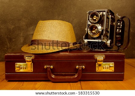 Old vintage camera  with fedora hat on rustic briefcase