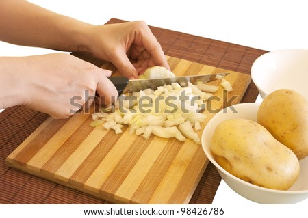 Beautiful women\'s hands cutting onion cubes, isolated on a white background. Potato and onion meal ingredients prepared for cooking.
