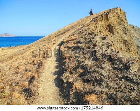 Photo. Sandy Cape, sea shore. Sunny day, the summer heat. Sea beach, blue sky. Path, path. Seaside resort. Bright light and contrast shadow of mountains.