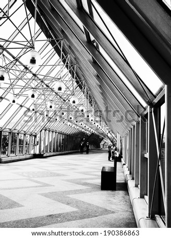 Photo, bridge in Moscow, Russia. Indoor glass bridge for pedestrians. Sunny day, bright light and contrasting shadows. Path, road, lights