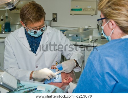 A dentist and assistant prepare a patient for a root canal