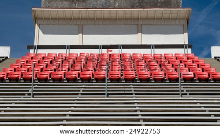 An empty stadium section with bleachers, reserved seats, and a press box