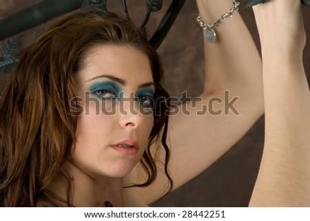 A sultry young woman grasps an iron bed frame