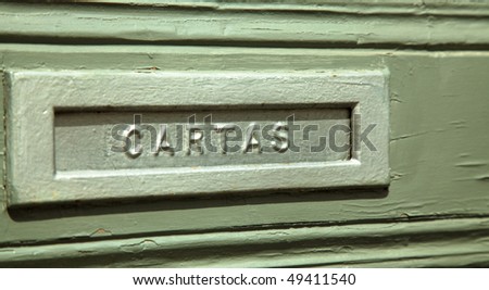 A metal mail slot in a wood door in Portugal