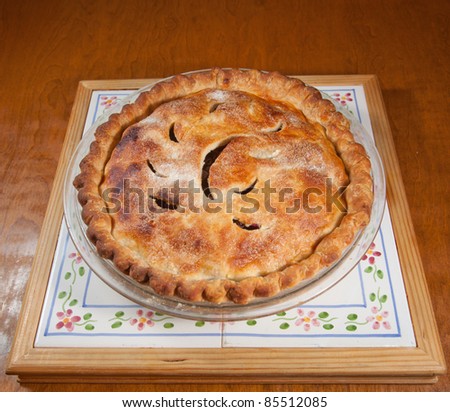 A warm blueberry pie, right out of the oven, sits on a table, ready to eat.