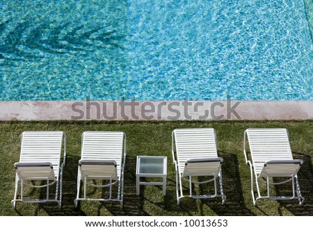 Ready for you -- a row of white lounge chairs by a resort pool.