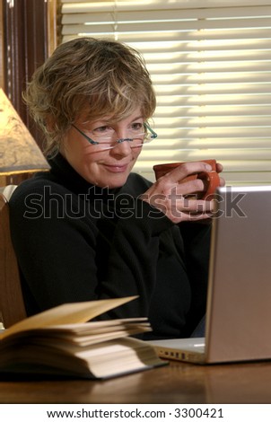 A middle age female works on her laptop computer from home.