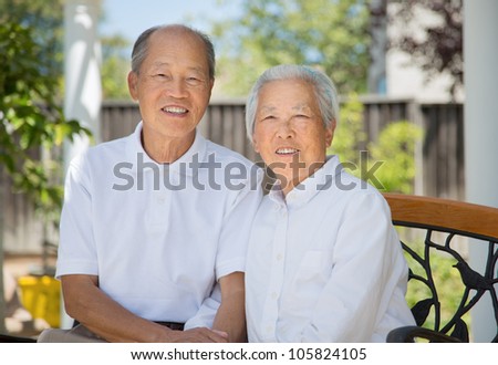Happy Smiling Chinese Elderly Sitting on Garden Chair Backyard