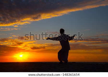 Chinese Elderly Woman Performing Taichi Outdoor by the beach under sunset sunrise silhouette