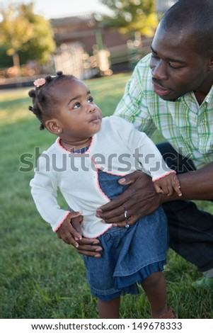 Little Smiling African American Girl Playing with Dad Outdoor