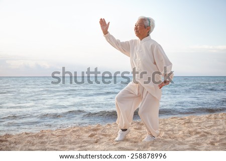 Chinese Elderly Woman Performing Taichi Outdoor by the beach under sunset sunrise