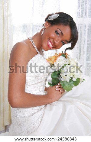 Beautiful Young Bride Sitting by the Window With Bridal Rose Bouquet
