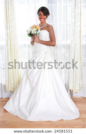 Beautiful Young Bride Looking Out Window In a Rainy Day With Bridal Rose Bouquet